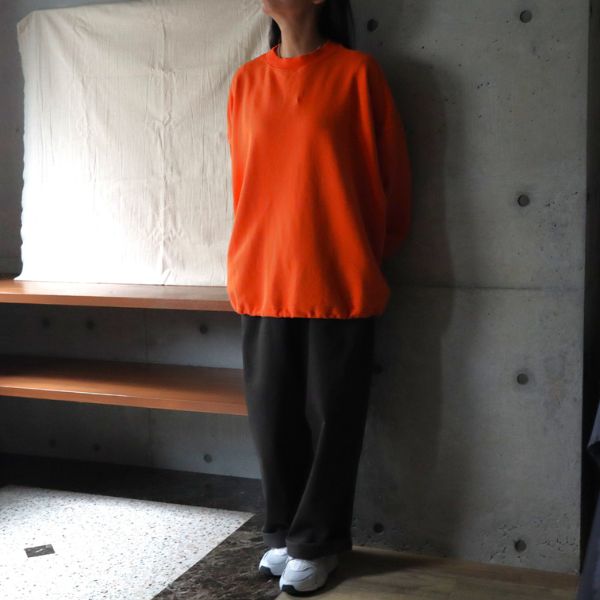 サンセットオレンジのセントラル裏毛ワイドトレーナーとチャコールのカツラギノッポパンツを合わせた全身正面コーデ。裾を絞った丸みのあるシルエットが特徴の2WAYトレーナーで、大人の初冬カジュアルを表現。