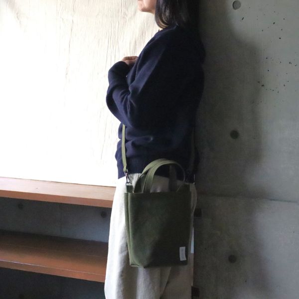 ネイビーのシャツを着た女性がカーキの８号帆布トートを斜めがけにした横向きウエストショット