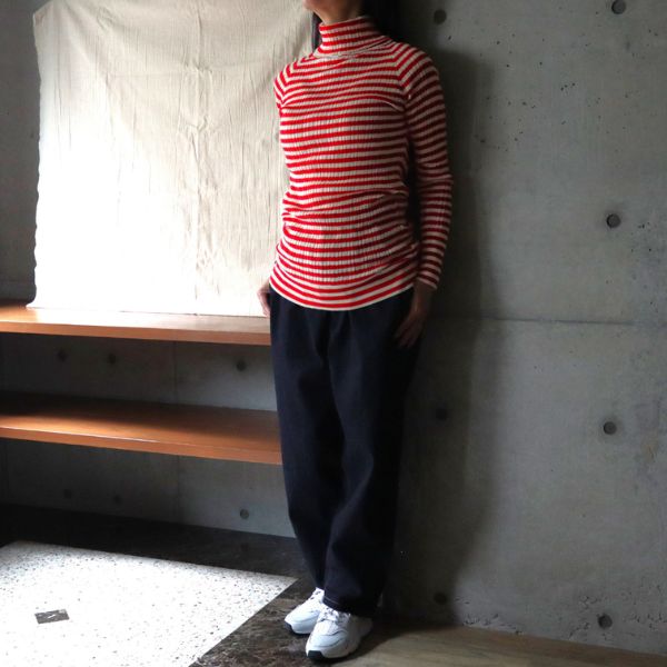 赤と白のストライプタートルネックとインディゴデニムのコージーパンツを着用した大人カジュアルコーデ。ナチュラルで快適な秋冬スタイル。全身正面写真です。