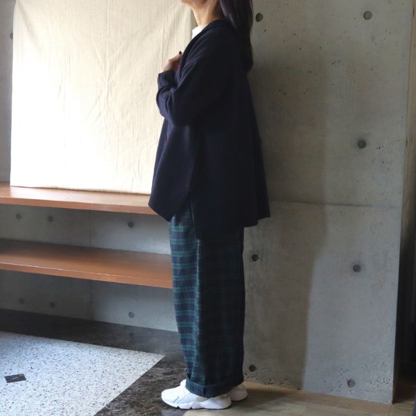 ネイビーのAラインカーディガンとグリーンチェックのノッポパンツを着用した女性の全身横向きコーデ写真