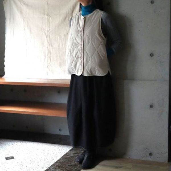 ベージュの万能ベストをターコイズブルー×グレーのカットソーとデニムロングスカートに合わせた全身コーデ。ナチュラルで季節感のある秋冬スタイル。