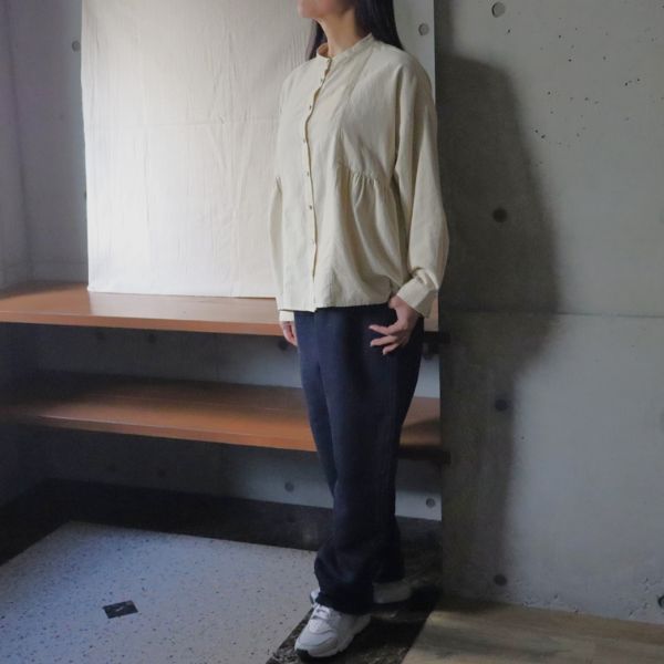 細畝コーデュロイ脇ギャザーブラウスとムラデニム裏起毛コージーパンツを着た女性の正面全身写真。冬のナチュラルスタイルを大人らしく楽しむ上品なコーデ。