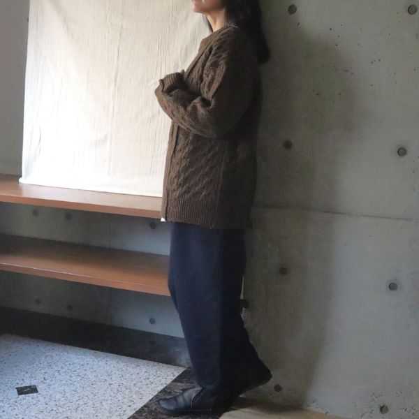 杢ブラウンのNATURAL COLORED WOOL柄編みニットに、インディゴの裏起毛エッグパンツを合わせた女性の横向き全身コーデ。ドロップショルダーの自然な抜け感を楽しむ、大人ナチュラルな冬スタイル。