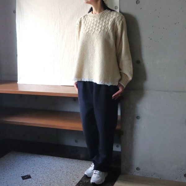 やさしいエクリュのミラノラムアンティークバスケット柄バイカラーニットに、深みのあるインディゴのムラデニム裏起毛コージーパンツを合わせた大人ナチュラルな冬コーデの全身正面写真。上質な温もりとすっきりとしたシルエットが魅力のスタイルです。