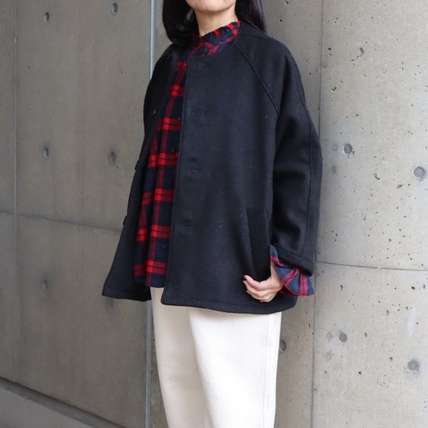 起毛チェックブラウスと裏起毛デニムにダブルフェイスメルトンコートを羽織った女性の膝上写真