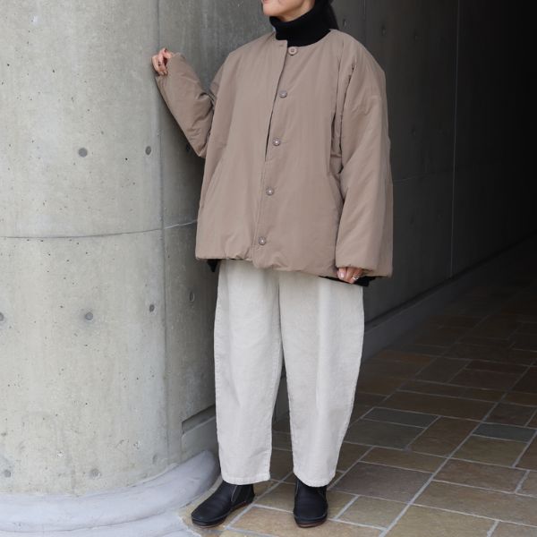 ブラウンのノーカラーレギュラーコートに、キナリのコーデュロイパンツを合わせた全身コーデ。ピーチ起毛のやわらかな質感とベージュの優しい色味が、冬らしいあたたかみを感じるスタイル。