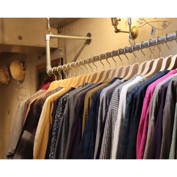 覚王山にあるセレクトショップ「コッピアーナ」の年末の様子。ナチュラルウェアが並ぶハンガーラック。オープン初年度の感謝を伝える落ち着いた雰囲気の写真。