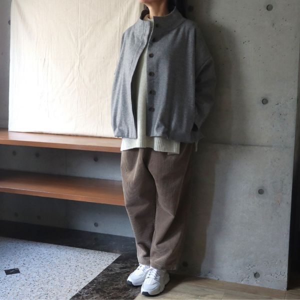 グレーのウールツイードハイネックショートジャケットに、オートミール色のニットとベージュのコーデュロイパンツを合わせた全身コーデ。やわらかいトーンでまとめた優しい冬のスタイル。