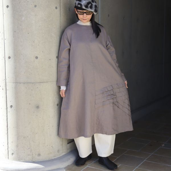 アッシュグレーの裾タックデザインワンピースのインナーに、アイボリーのシルクベールハイネックを重ね、キナリの8オンスムラデニムエッグパンツを合わせた全身正面コーデ。やわらかな色合わせと天然素材の重ね着で、落ち着いた大人ナチュラルな雰囲気に。