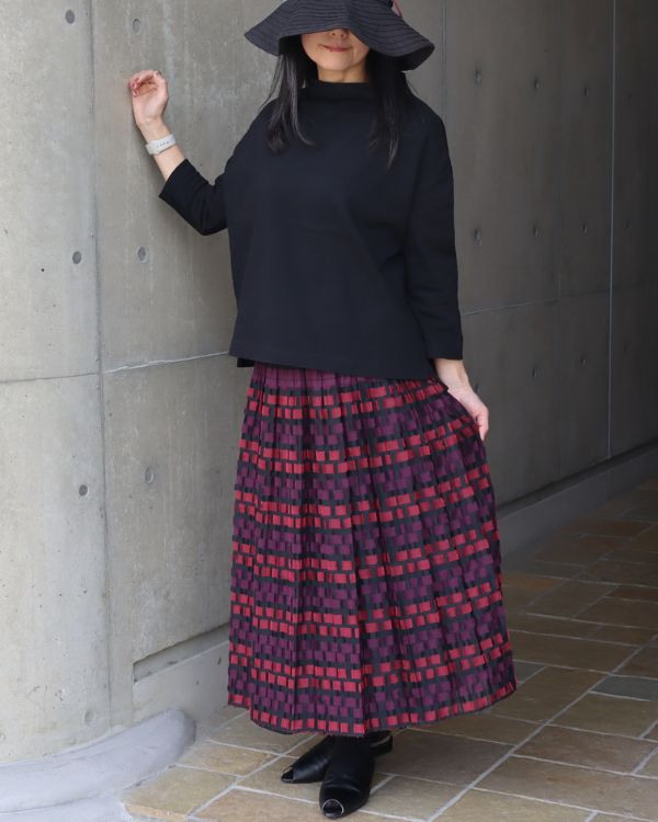 米沢織のリバーシブルカットジャカードスカート(ピンク柄)を黒トップスと合わせた上品な全身コーディネート。