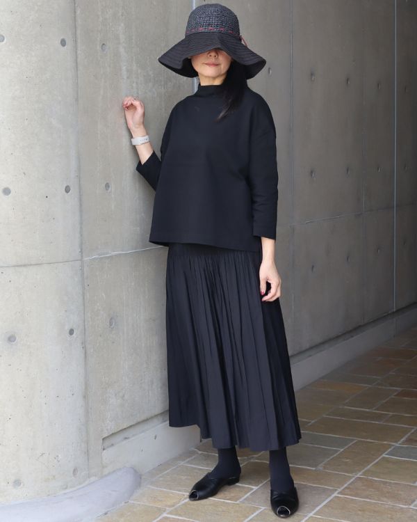 米沢織リバーシブルスカートを裏返し、黒無地面で着用したシンプルで洗練された全身スタイル。