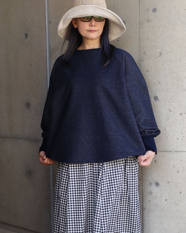 デニムニットトレーナーの裾デザインと柔らかな素材感を確認できる腰上の正面ディテール写真
