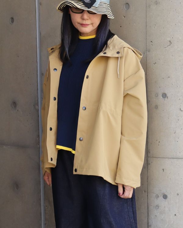 T/Cウェザー撥水マウンテンパーカーを着た女性の腿上正面写真。軽量で上品な素材感とミニマルなデザインが魅力の大人アウター。