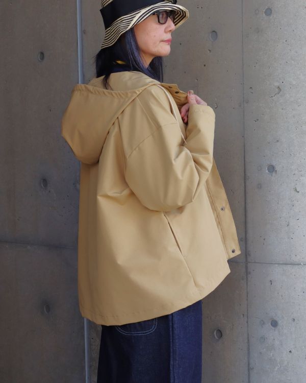 T/Cウェザー撥水加工のマウンテンパーカーを着た女性の斜め後ろ腿上写真。カジュアルときれいめを両立する大人ナチュラルな春アウター。