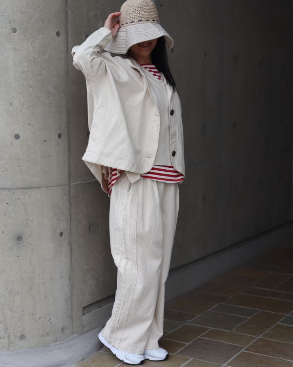 6.5オンス綿麻デニムのフードバルーンジャケットとサイドテープパンツをセットアップで着用した春の大人デニムコーデ写真｜ナチュラル色斜め横向き全身