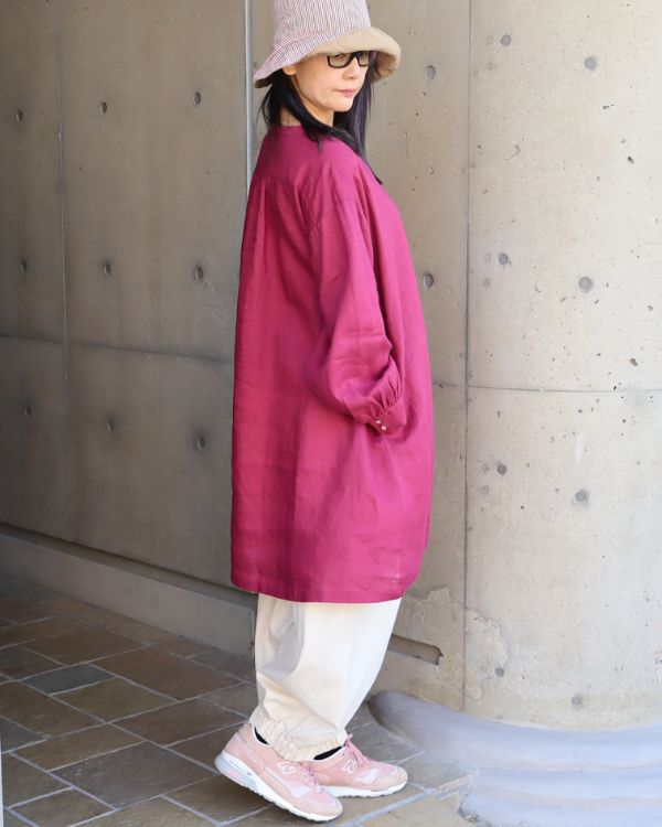 横向きから見たワインレッドのボリューム袖ヘンリーあきチュニックとキナリのポップパンツを着用したナチュラル大人女性の全身コーデ。チュニックの丈感とパンツの丸みあるシルエットが分かる写真。