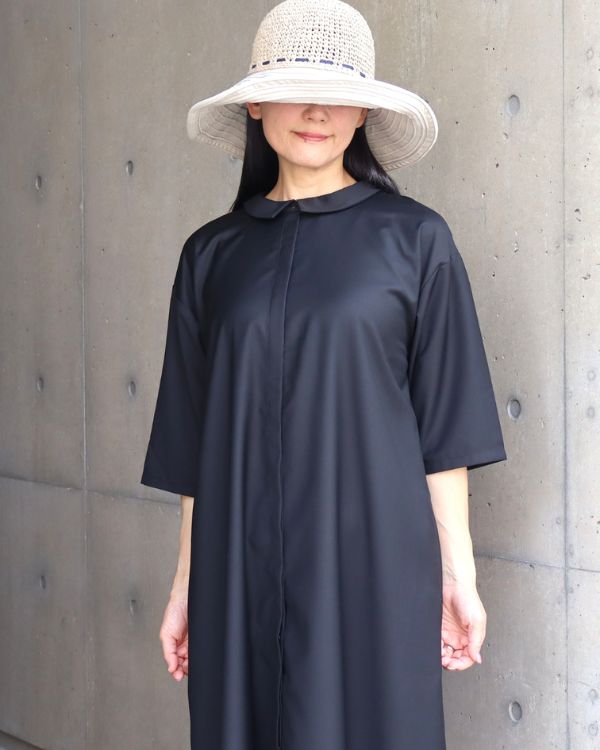 名古屋・覚王山のセレクトショップ コッピアーナでご紹介する、ブラックの2way襟付きワンピースを比翼仕立て側を前に着用した上半身写真です。すっきりとした比翼デザインが上品な印象を与え、前後どちらでも着用できる2way仕様の魅力を紹介しています。