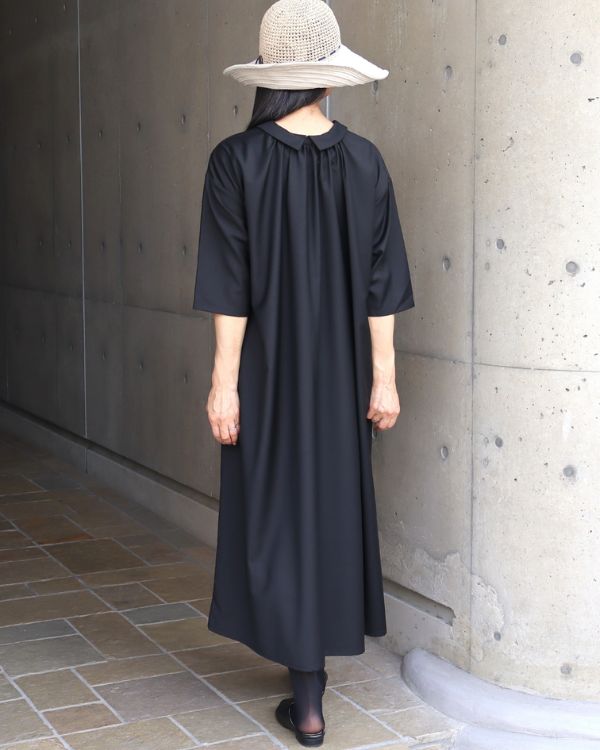 名古屋・覚王山のセレクトショップ コッピアーナでご紹介する、ブラックの2way襟付きワンピースをギャザー側を前に着用した後ろ姿の写真です。背中から裾へと流れる美しいシルエットが印象的で、前後どちらでも着られる2way仕様ならではの上質な着こなしを紹介しています。