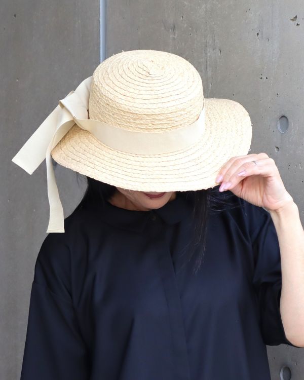 名古屋・覚王山のセレクトショップ コッピアーナでご紹介するラフィアリボンハット。天然素材ラフィアのやさしい編み目とナチュラルカラーのリボンが美しく映えるアップ写真で、夏の装いに上品な季節感を添えるアイテムです。
