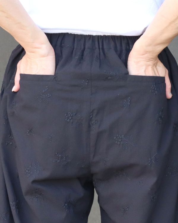 麻(リネン)調ポプリン オリーブ柄刺繍istaパンツのブラックを後ろから撮影した着用写真。後ろポケットやシルエットの美しさが伝わり、季節を問わず快適に着回せるパンツとして、名古屋・覚王山のコッピアーナがおすすめしています。