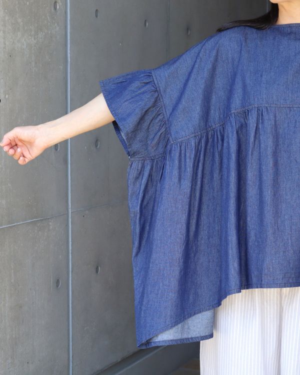 コットンデニムワイドブラウスの前身頃を近くから撮影した写真。やわらかなライトデニムと繊細なギャザーの表情がよくわかり、一枚で着映えする上品なデザインを感じていただけます。