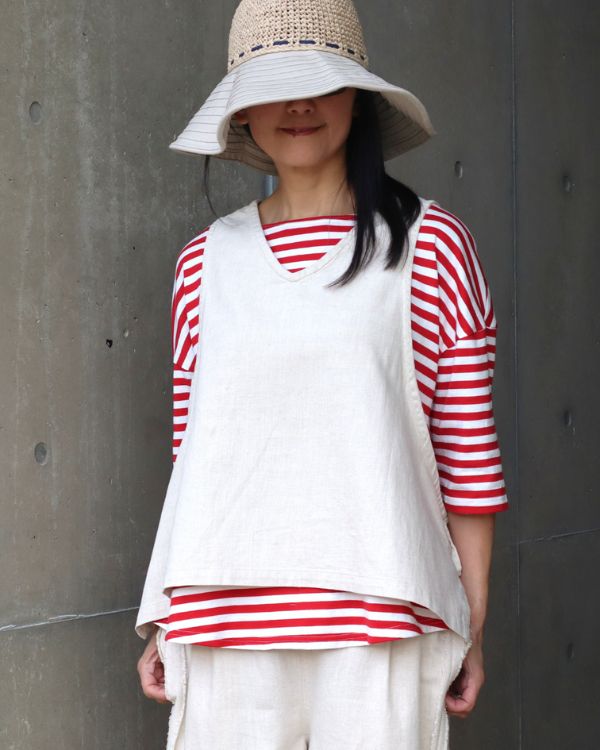 6.5oz甘撚りデニム サイドリボン2WAYベストのオフカラーをレッドストライプTシャツに合わせた上半身写真。Vネックデザインとやわらかな綿麻素材の質感が分かりやすく、普段使いからお出かけまで活躍する着こなしを名古屋・覚王山のコッピアーナよりご紹介しています。
