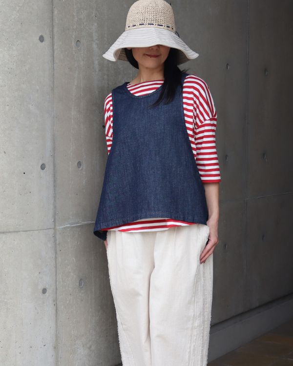 6.5oz甘撚りデニム サイドリボン2WAYベストのブルーカラーをレッドストライプTシャツに重ねた全身コーディネート。前後2WAY仕様ならではの着回しを楽しめる一枚として、名古屋・覚王山のコッピアーナがおすすめする大人ナチュラルな装いです。

