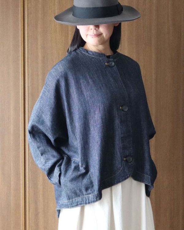 名古屋・覚王山のセレクトショップ、コッピアーナのインディゴのバルーンジャケットを斜め前から撮影した上半身写真。やわらかな6.5oz綿麻甘織りデニムの風合いと大きめの釦が伝わり、秋の装いに上質な表情を添えています。
