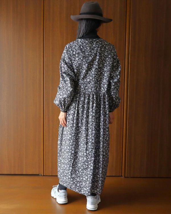 名古屋・覚王山のコッピアーナで撮影した、ブラックのフラワープリントキーネックワンピースの後ろ姿です。前後身頃のギャザーがつくるゆったりしたシルエットで、一枚でも重ね着でも楽しめます。